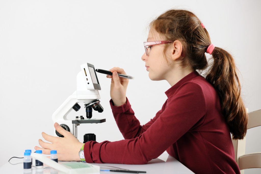 schoolgirl with modern microscope