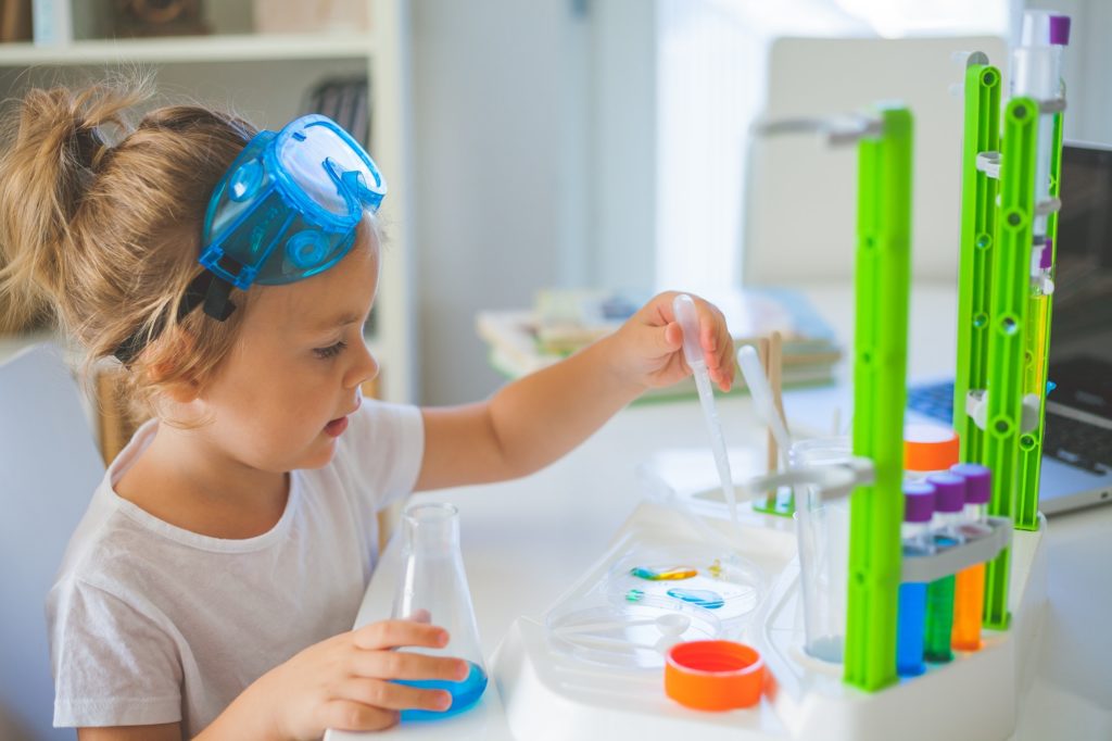 The science. A cute little girl is doing experiments at home.